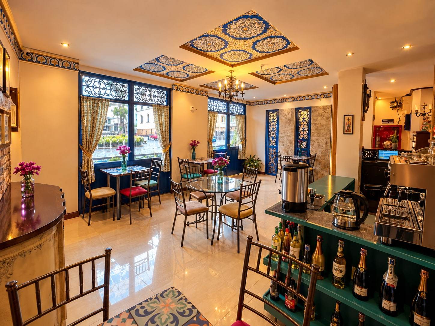 Cafetería del hotel con techo decorado en azul, mesas y barra de café