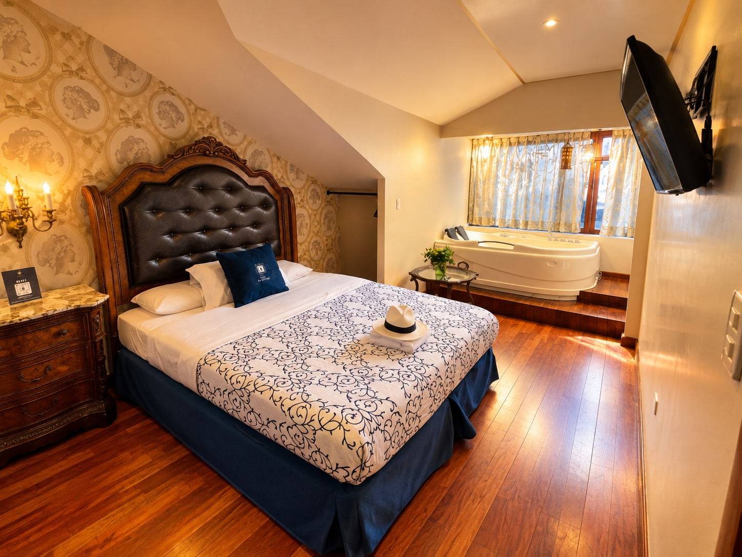 Habitación con cama de cabecera capitoné y jacuzzi junto a la ventana