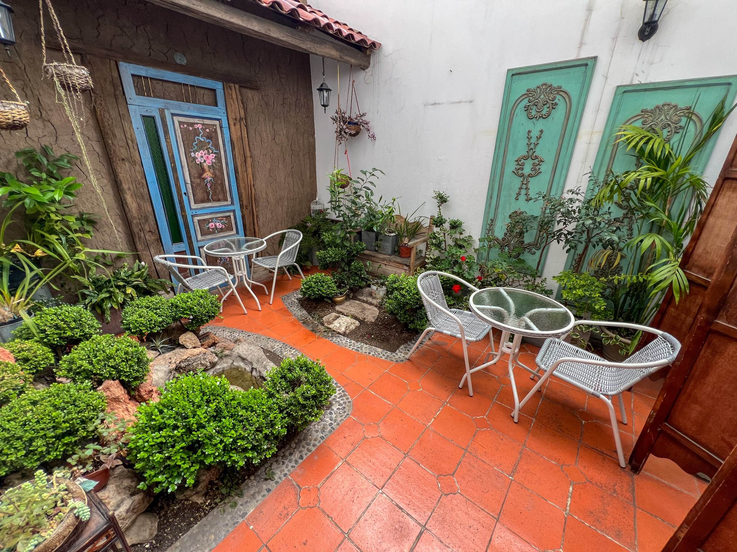 Patio interior con plantas, piso de ladrillo y mesas para sentarse