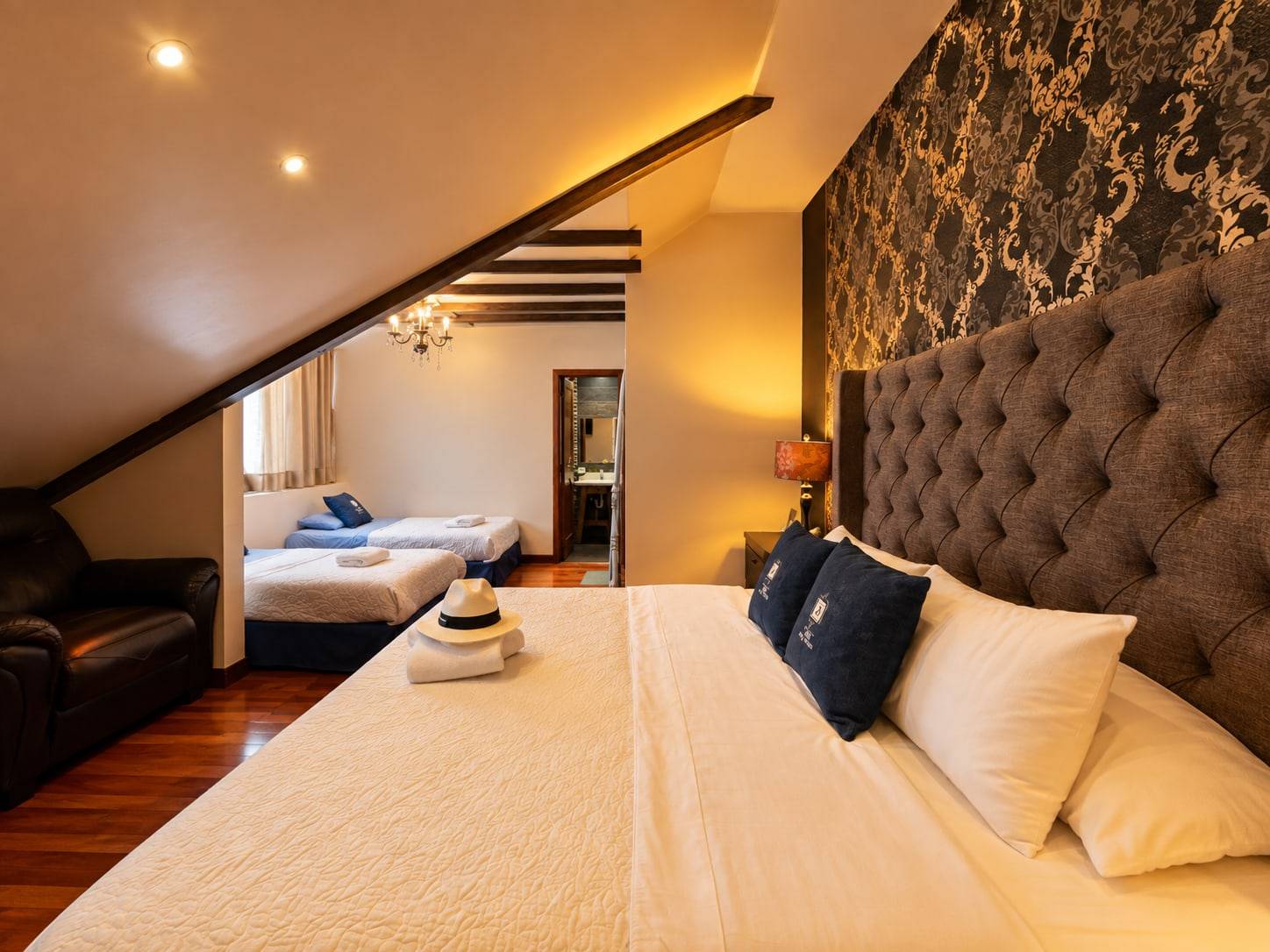 Habitación familiar con cama grande en primer plano y dos camas individuales al fondo